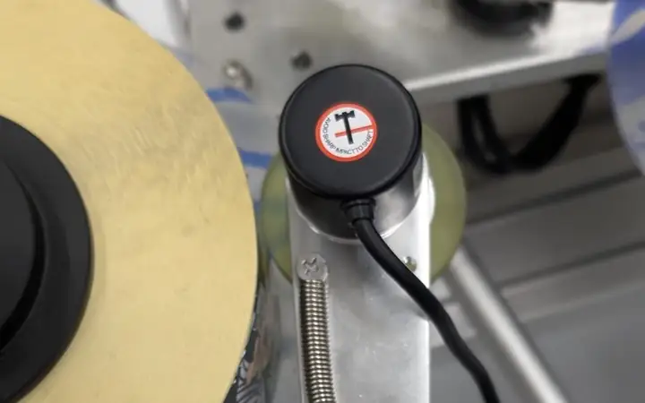 Encoder met meetwiel die de bandsnelheid doorgeeft aan de printer