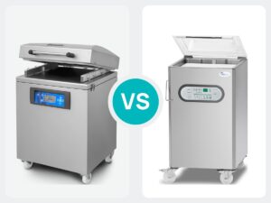Twee vloermodel vacuummachines naast elkaar, een Henkovac en een Boss, met een VS-teken ertussen
